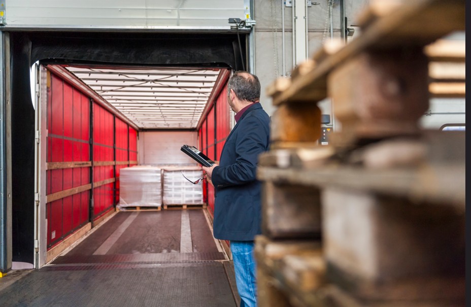 Stock manager looking at palleted goods on truck trailer
